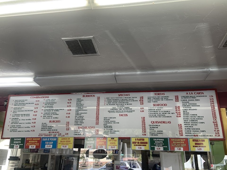 Menu board with tacos, burritos, and sides.
